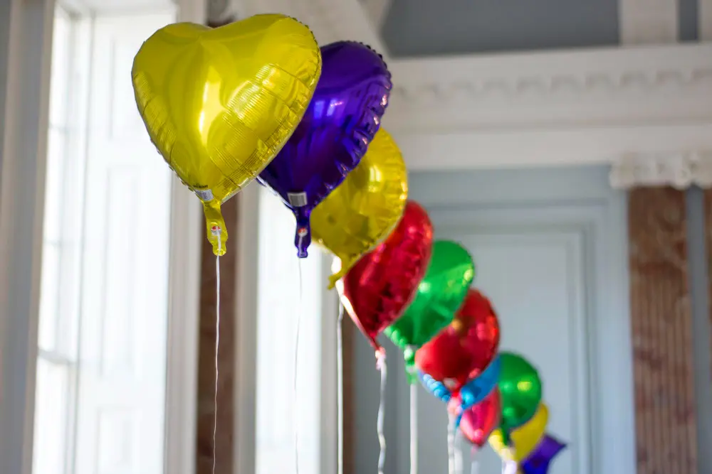 Balony z helem przywiązane tasiemkami do kolorowych ciężarków